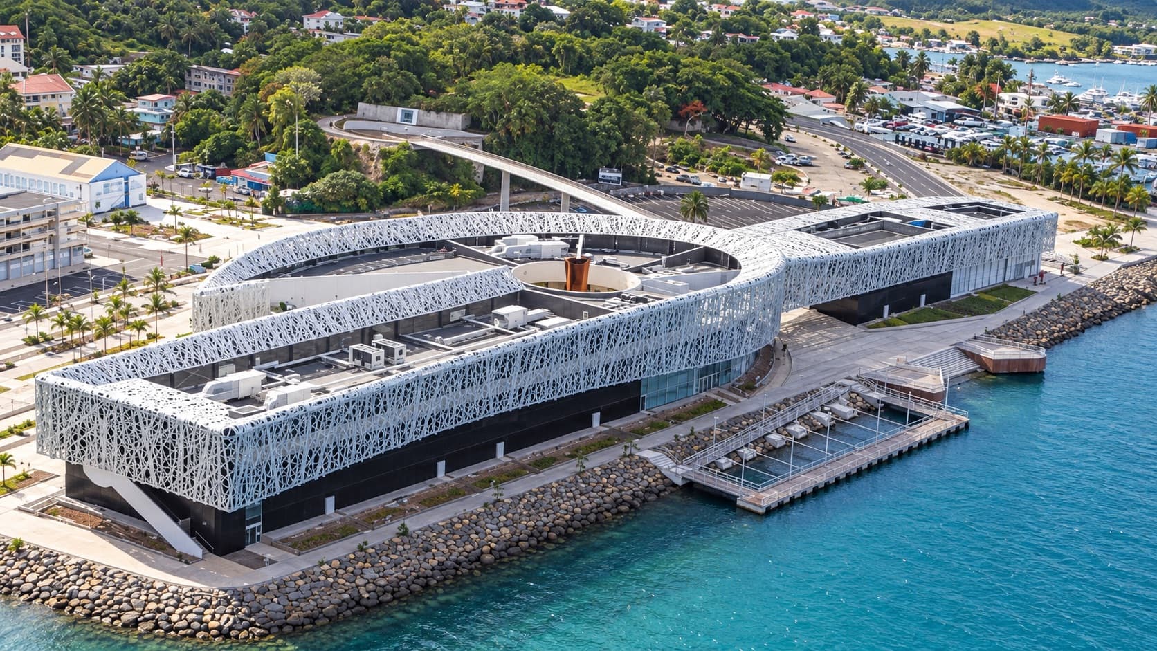 Vue aérienne d’un grand bâtiment blanc ajouré au bord de la mer, à Pointe-à-Pitre, en Guadeloupe.
